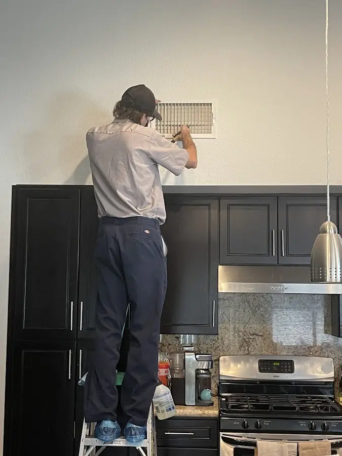 Technician inspecting an air vent during HVAC service in McNair